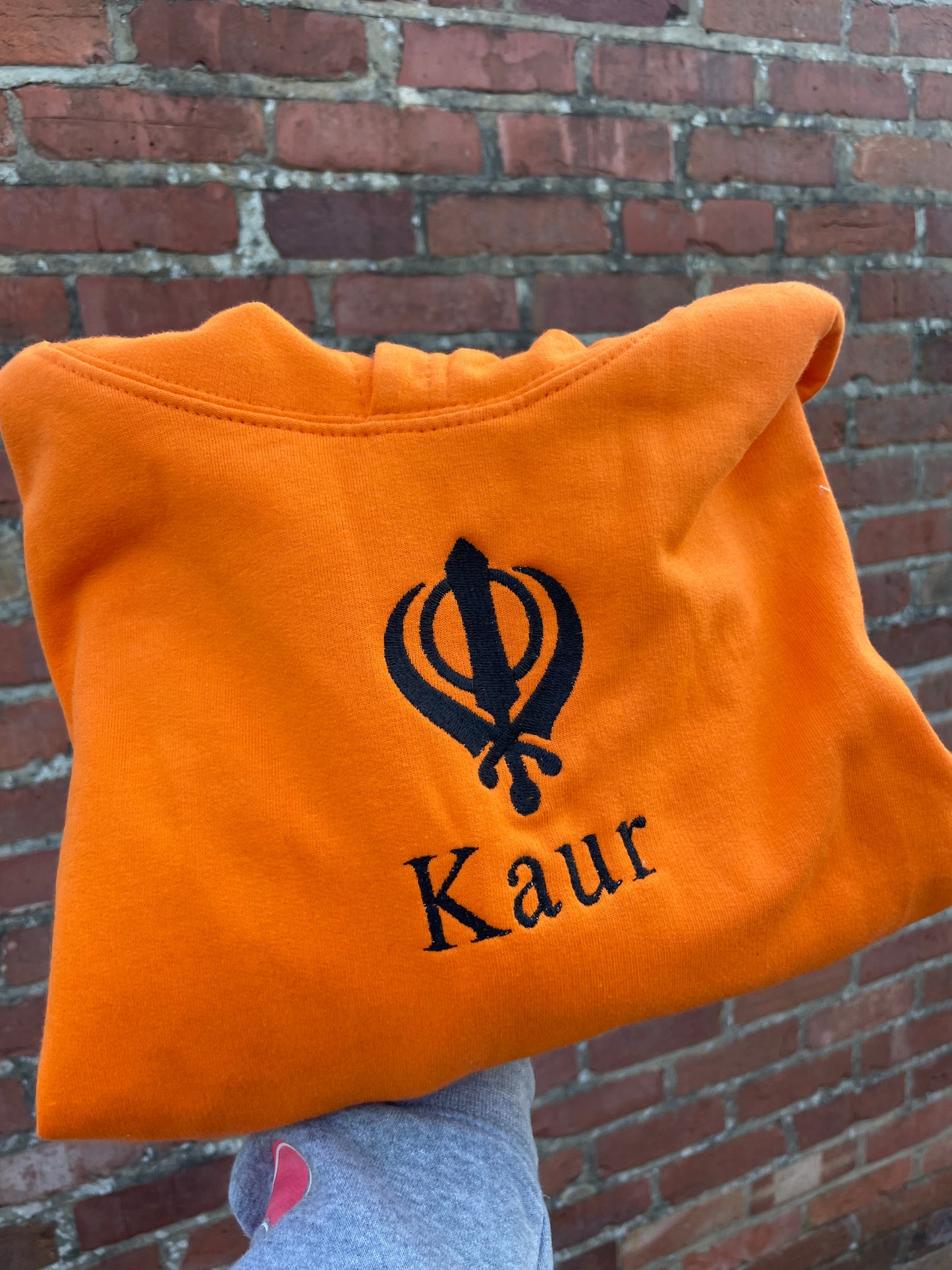 Experience ultimate style and grace with our Embroidered Kaur Orange hoodie. Made with intricate embroidery of the Kaur and Khanda, this hoodie exudes elegance and tradition. Elevate your wardrobe and embrace your identity with this unique and culturally significant piece.