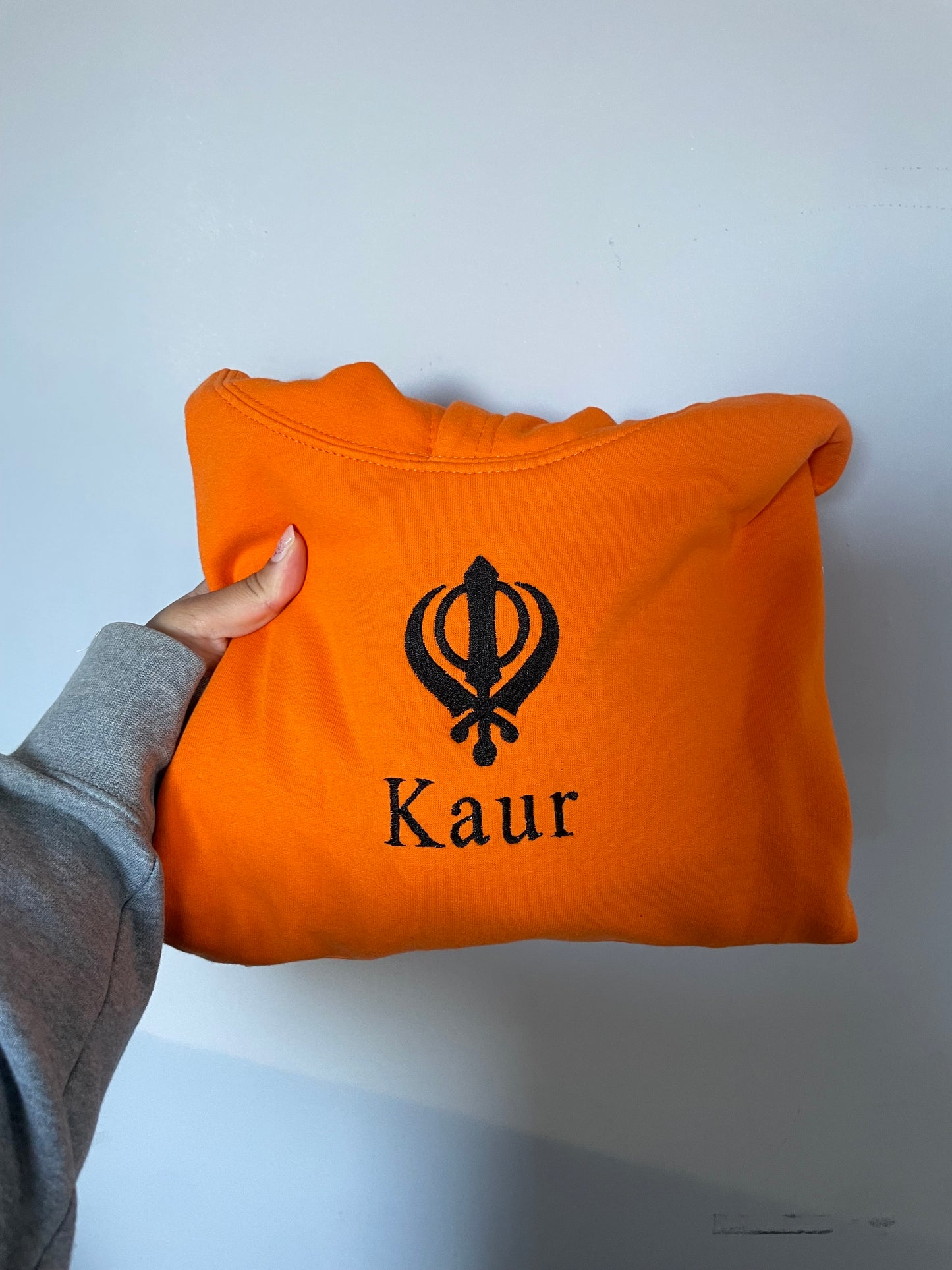 Experience ultimate style and grace with our Embroidered Kaur Orange hoodie. Made with intricate embroidery of the Kaur and Khanda, this hoodie exudes elegance and tradition. Elevate your wardrobe and embrace your identity with this unique and culturally significant piece.
