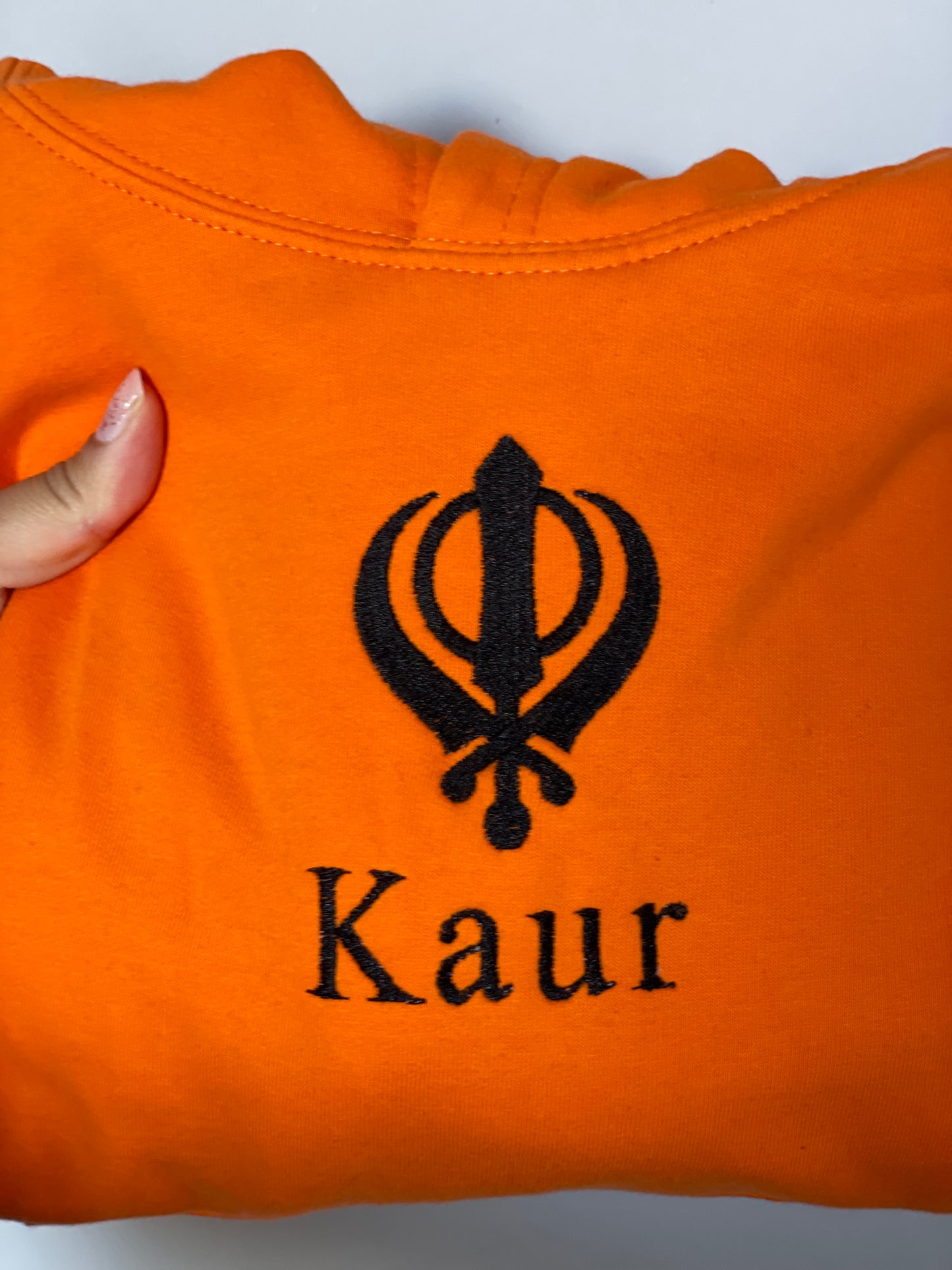 Experience ultimate style and grace with our Embroidered Kaur Orange hoodie. Made with intricate embroidery of the Kaur and Khanda, this hoodie exudes elegance and tradition. Elevate your wardrobe and embrace your identity with this unique and culturally significant piece.