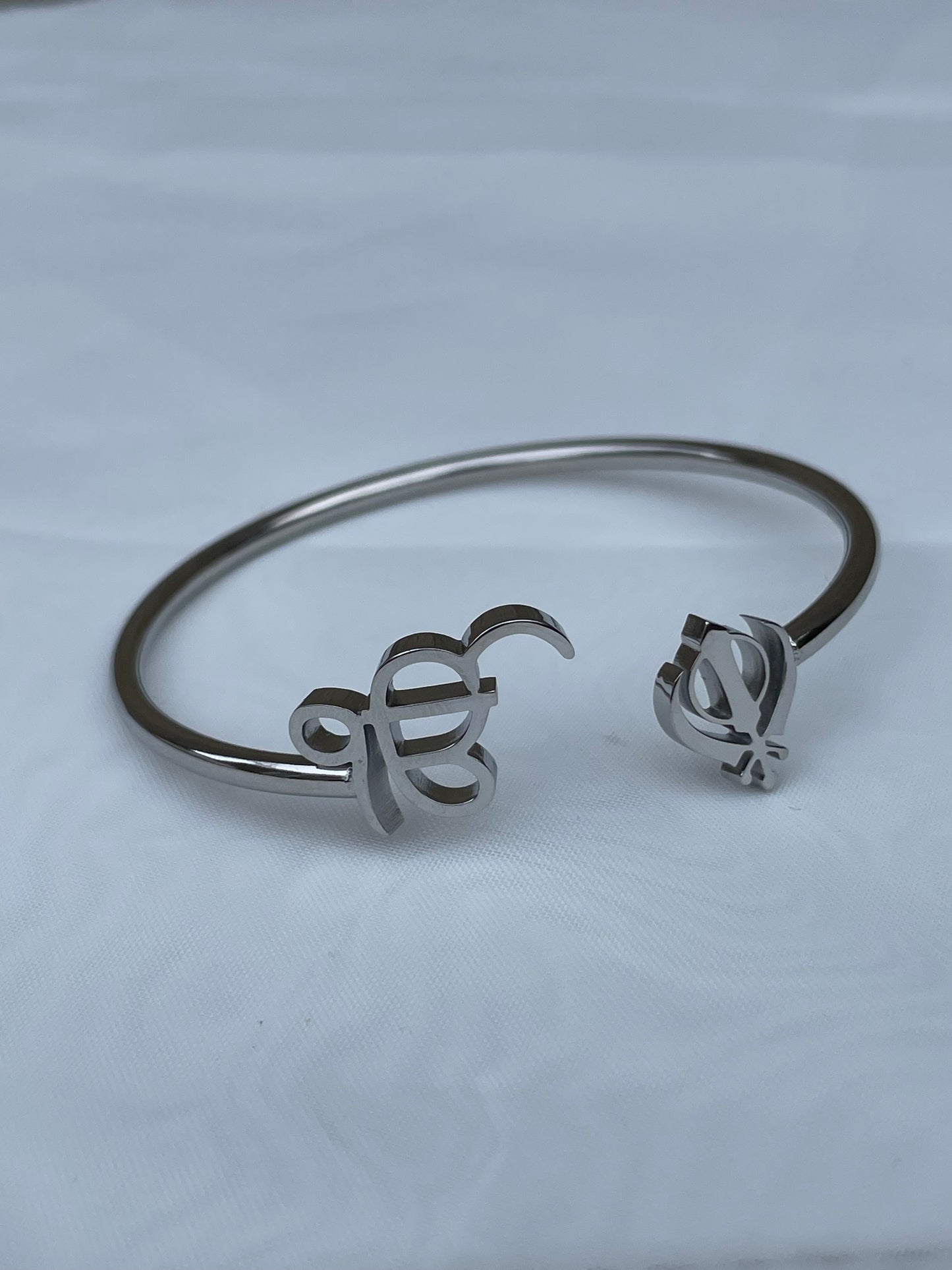 The Sikh Khanda Bangle Bracelets are a stunning representation of cultural pride and elegant fashion. Featuring the revered Ek Onkar and Khanda symbols, these bracelets are available in both gold and silver finishes, catering to different style preferences. They offer a unique blend of traditional symbolism and modern design, making them suitable for both everyday wear and special occasions. The design of the Sikh Khanda Bangle Bracelets is both sophisticated and meaningful. 