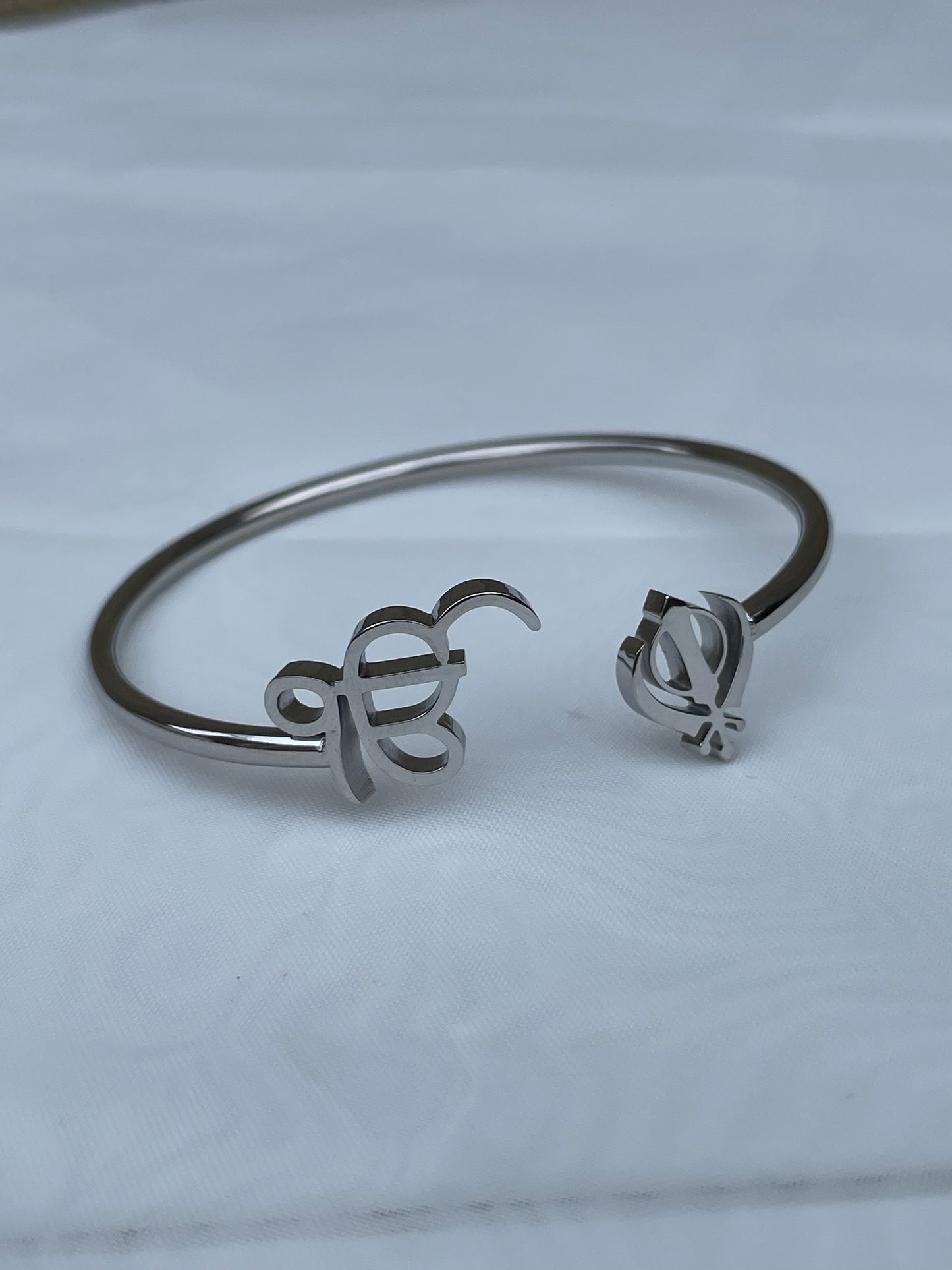 The Sikh Khanda Bangle Bracelets are a stunning representation of cultural pride and elegant fashion. Featuring the revered Ek Onkar and Khanda symbols, these bracelets are available in both gold and silver finishes, catering to different style preferences. They offer a unique blend of traditional symbolism and modern design, making them suitable for both everyday wear and special occasions. The design of the Sikh Khanda Bangle Bracelets is both sophisticated and meaningful. 